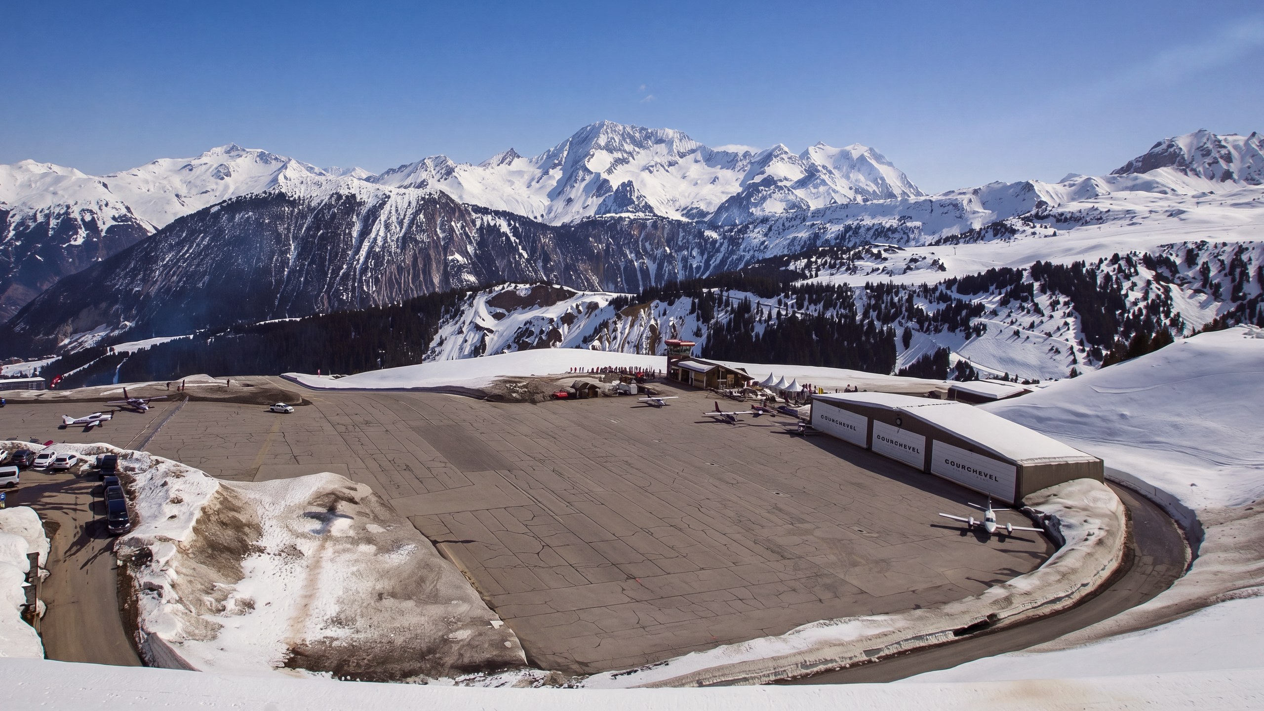 L'altiport de Courchevel vu d'en haut, ses hangars et son aire de stationnement enneigée, face aux sommets
