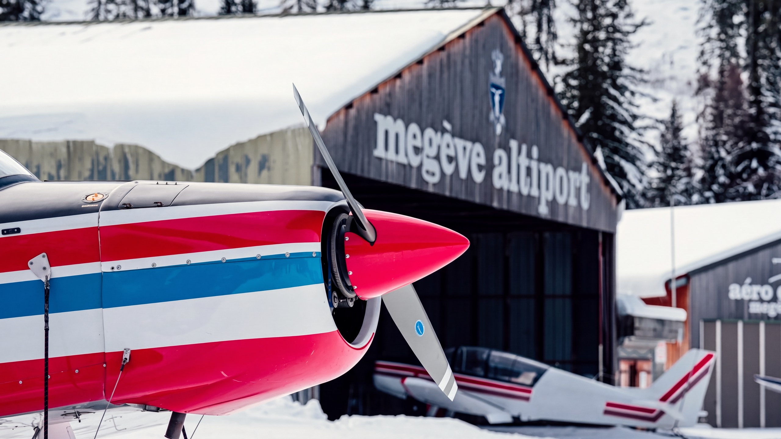 Le nez d'un petit avion devant le hangar de l'altiport de Megève, sous la neige