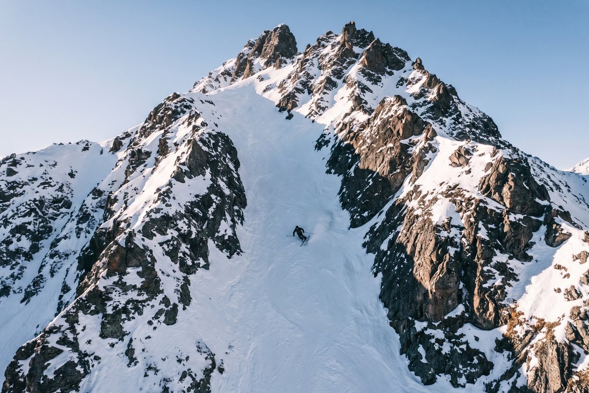 Skieur dans un couloir raide sous un sommet rocheux, à Courchevel