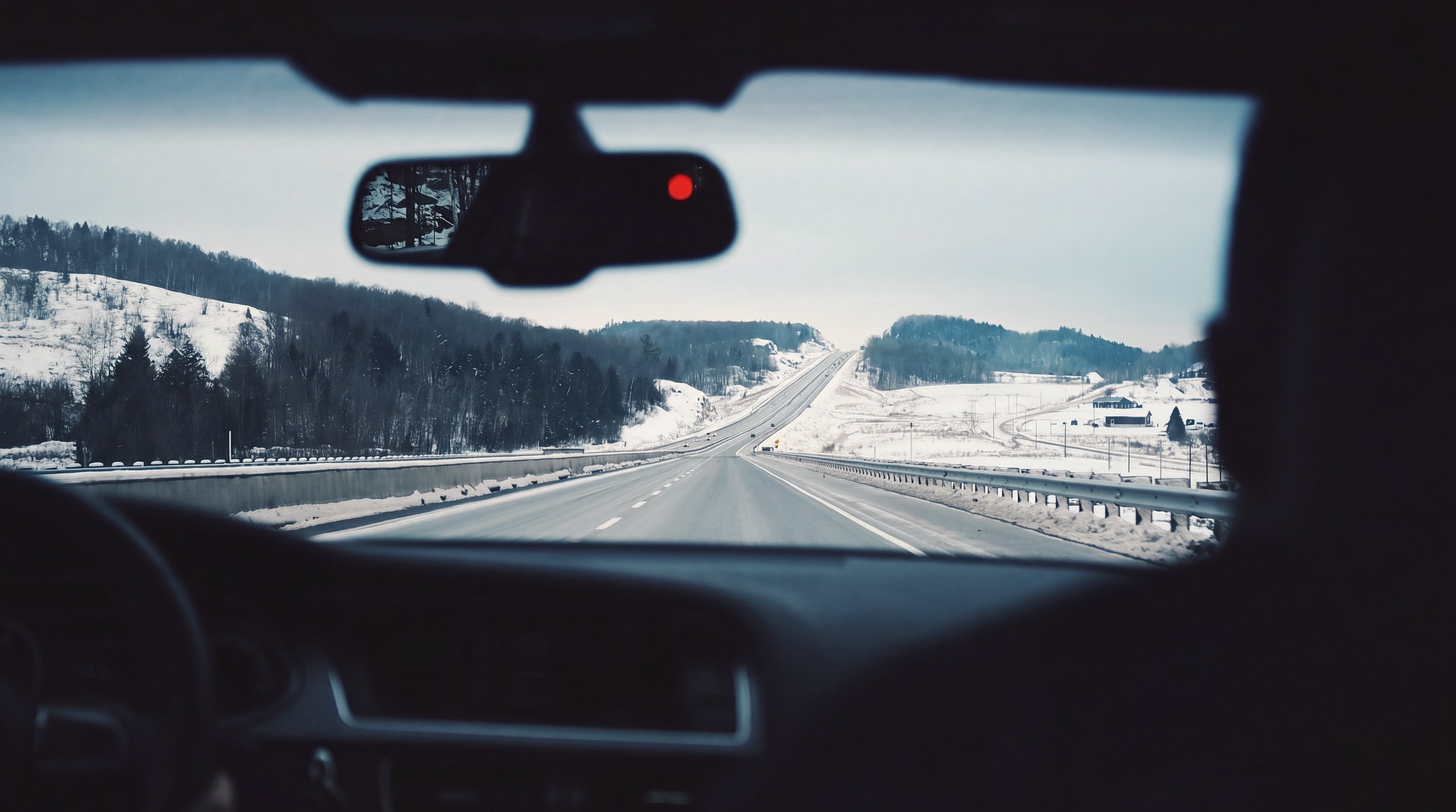 Une route de vallée enneigée vue depuis l'intérieur d'une voiture, en hiver