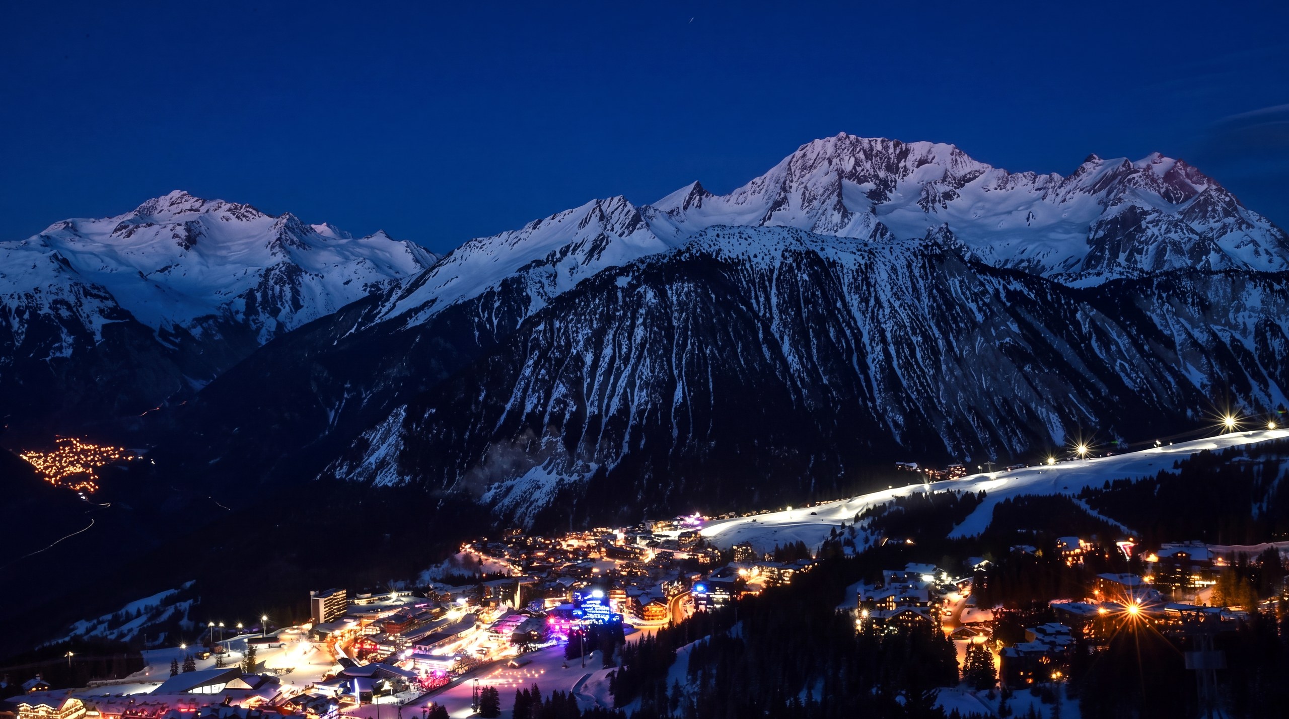 Les villages de Courchevel illuminés à la nuit tombée, sous les sommets enneigés
