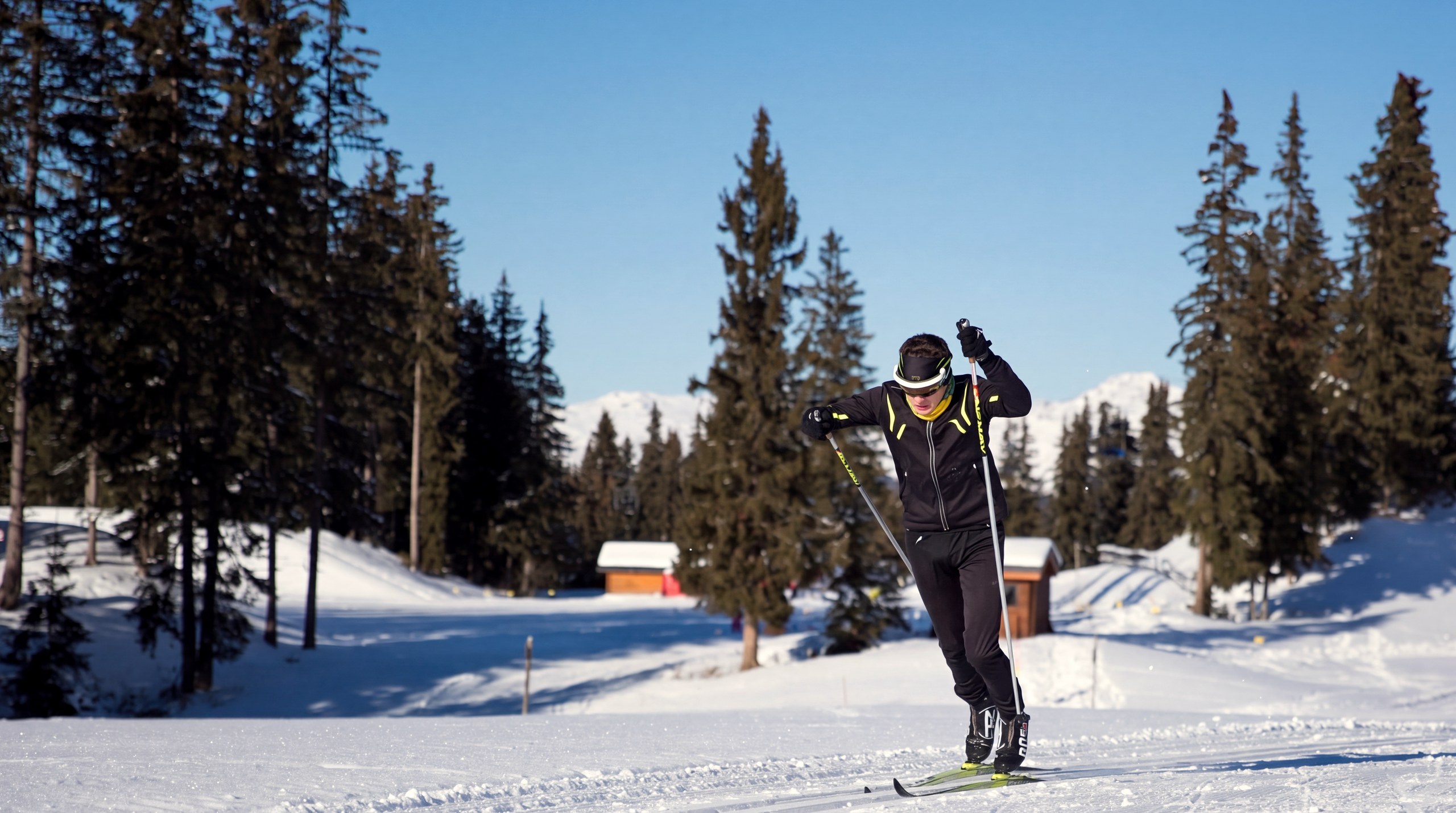 Un fondeur sur une piste de ski de fond de Méribel, entre les sapins, sous un ciel bleu